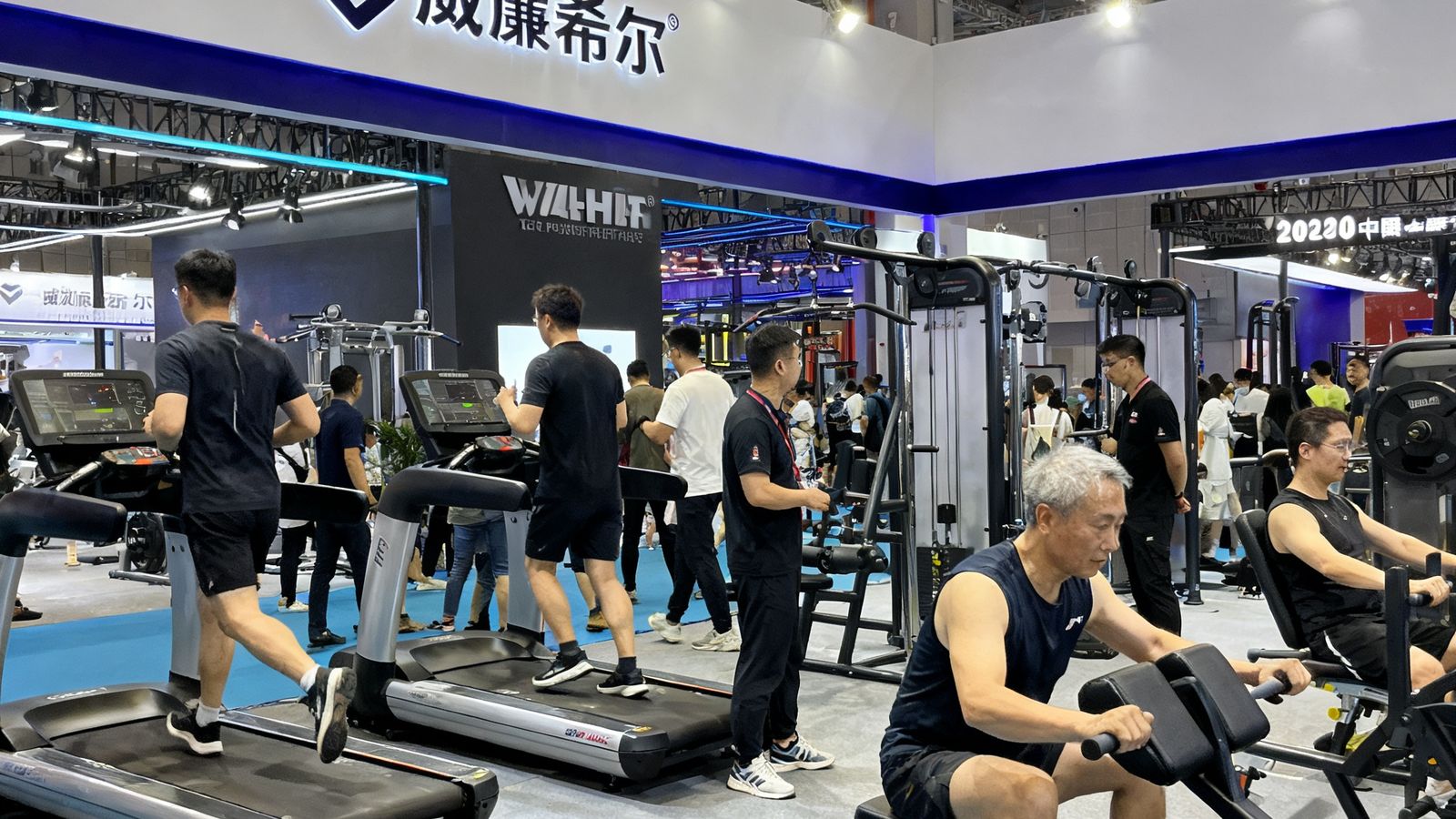 威廉希尔团队在2024中国健身产业博览会上的展位，展示多款最新健身器材，参观者正在体验设备